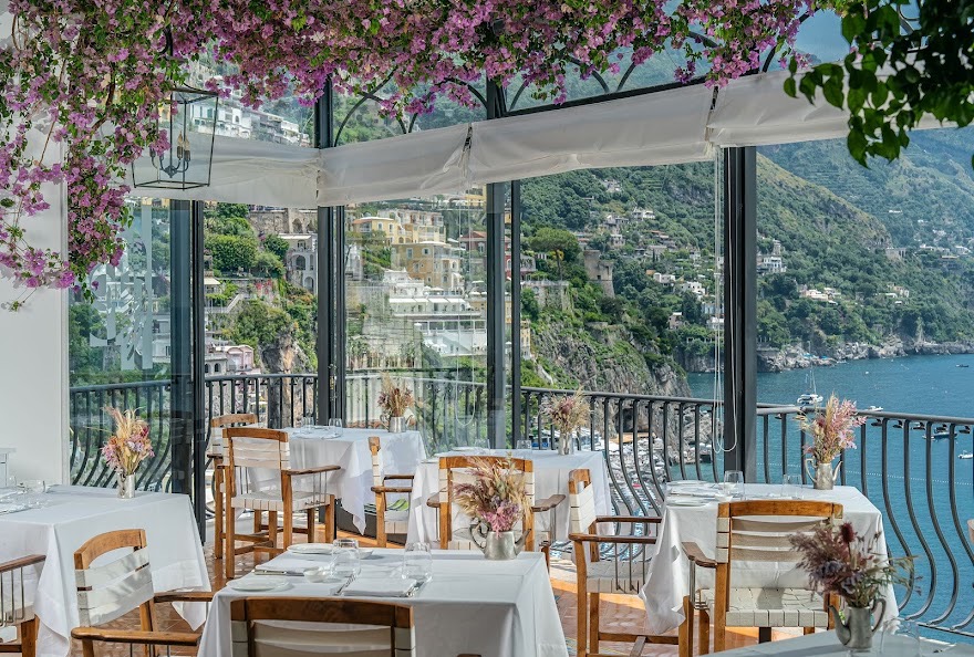 Ristorante Al Miramare bright dining room with flowers, white tablecloths, and Positano sea views